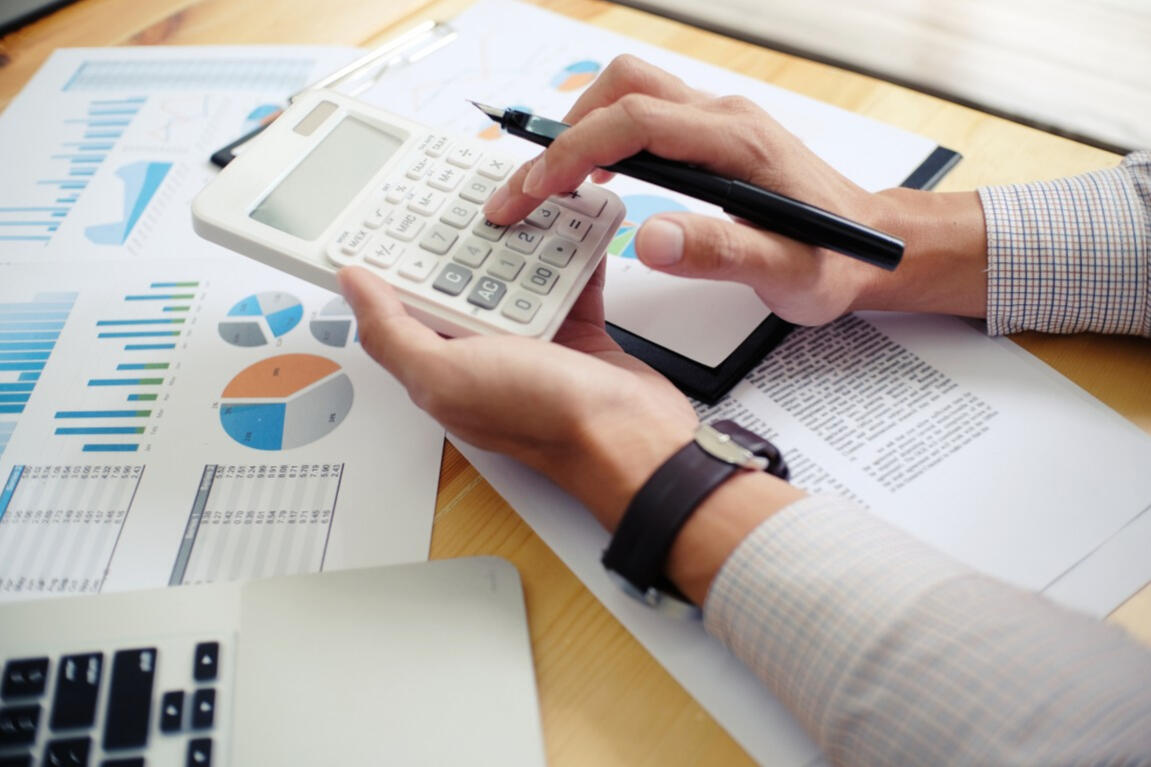 Person doing accounting tasks with a computer and calculator.